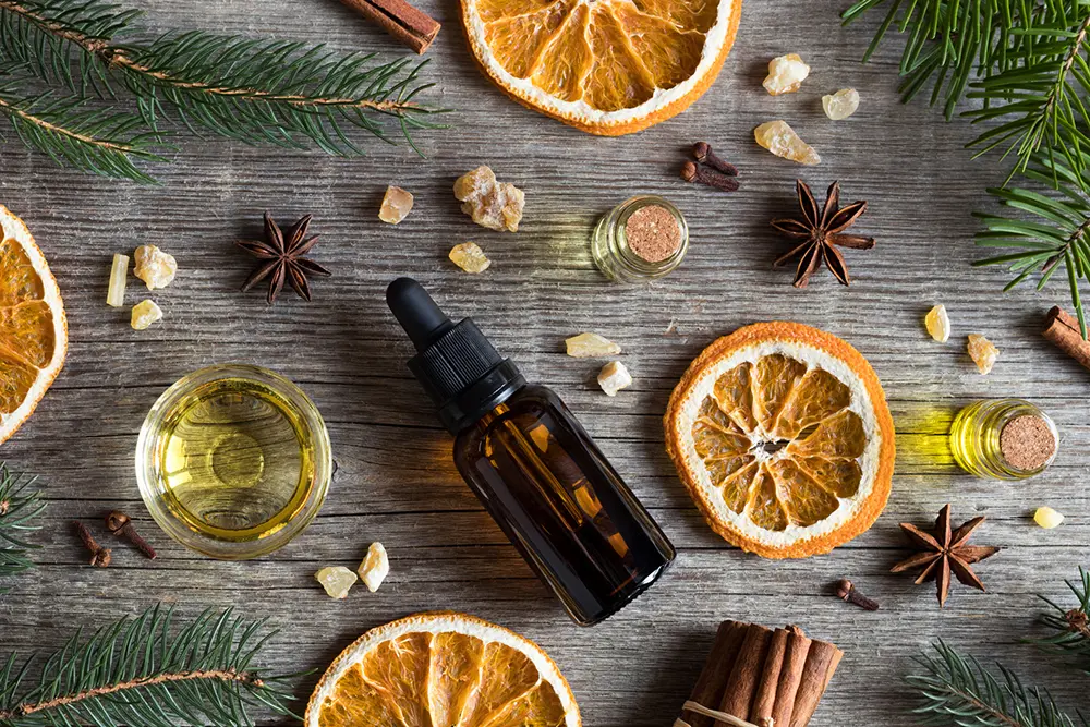 Bottles of oil surrounded by oranges, cloves and more