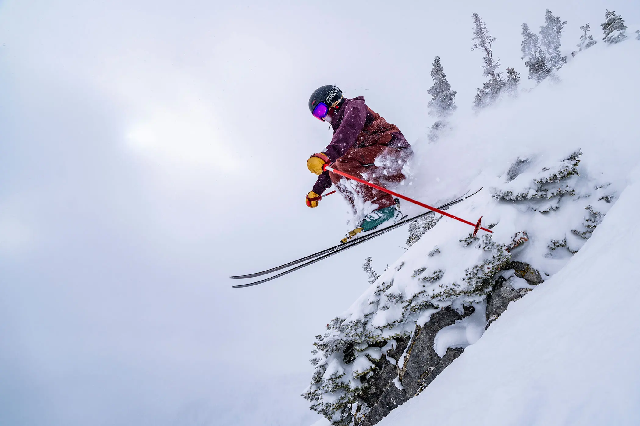Skier jumps off a cliff with Stay and Save lodging discounts at Snowbird.