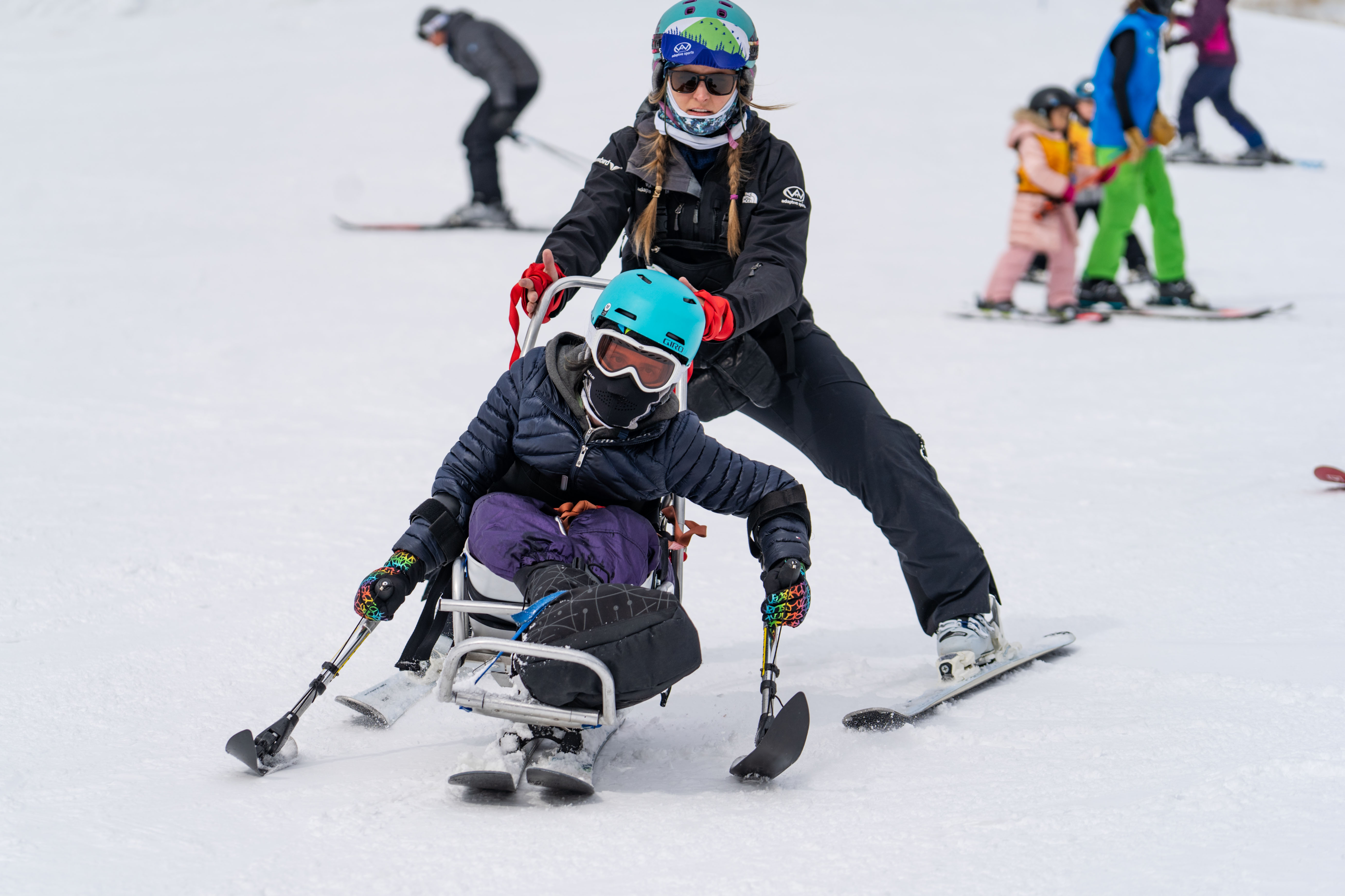 Wasatch Adaptive team member with a sit down skier at Snowbird